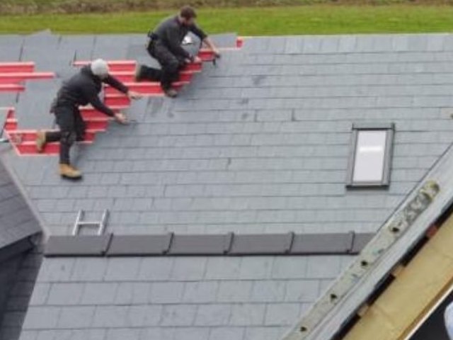 Velux roof window set into a new natural Spanish slate roof while the crew slate around it